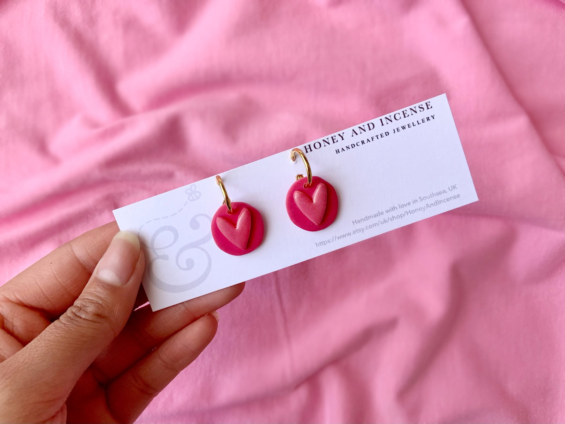 hot pink polymer clay earrings that resemble a button from a childrens toy, hot pink shimmery heart on gold huggie hoops