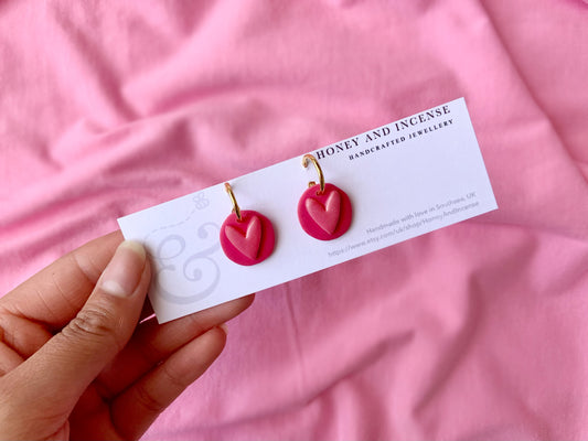 hot pink polymer clay earrings that resemble a button from a childrens toy, hot pink shimmery heart on gold huggie hoops