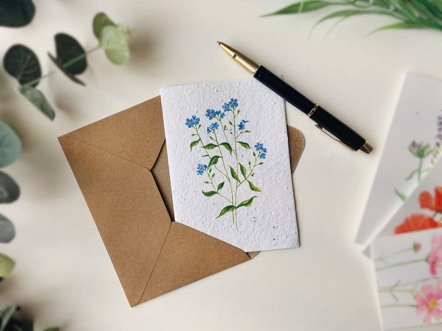 a greetings card containing seeds and a forget me not painting on the front.