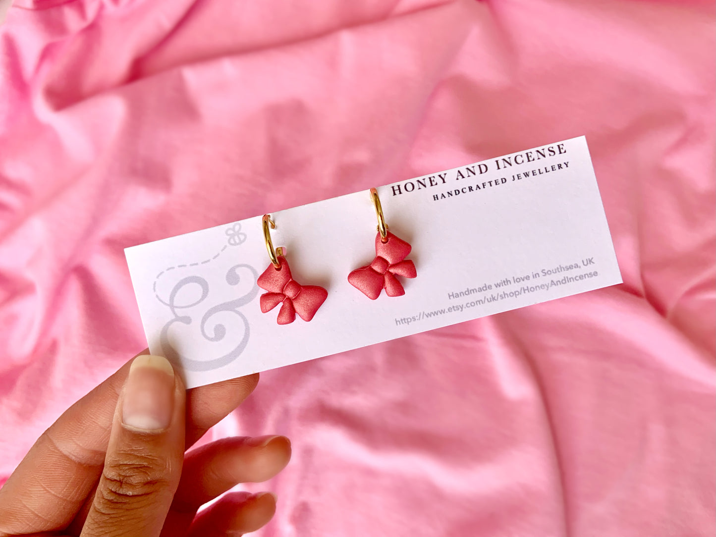 hot pink shimmery bow polymer clay earrings on gold huggie hoops