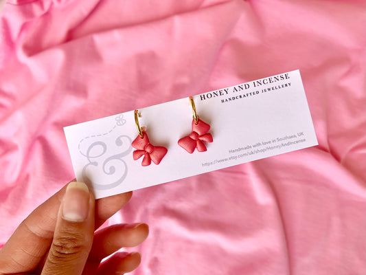 hot pink shimmery bow polymer clay earrings on gold huggie hoops
