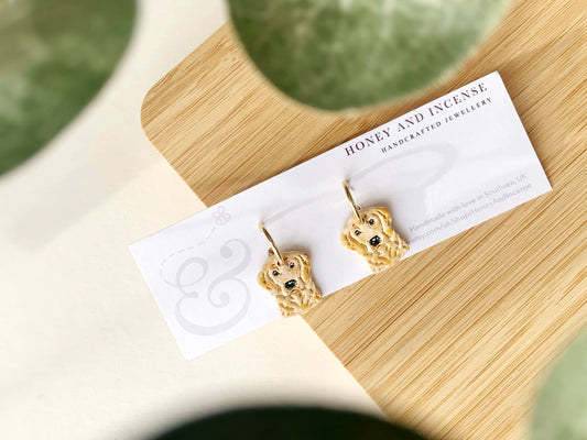 a pair of earrings made out of polymer clay, to look like golden retriever dogs.Hand painted with details to bring them to life, realistic looking!