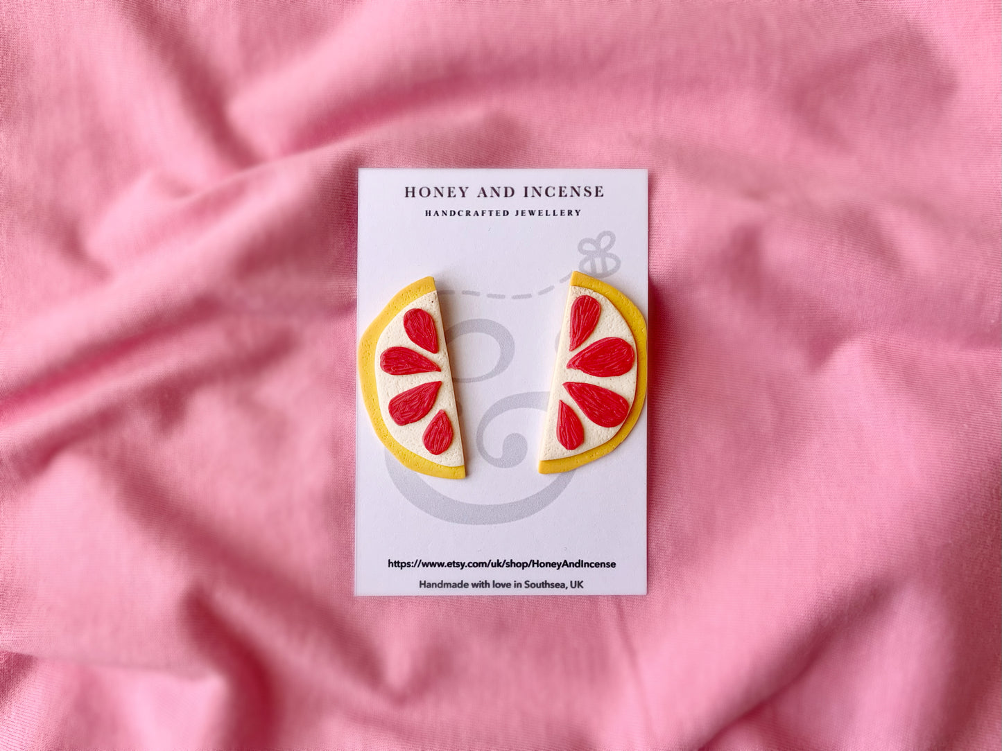 hot pink and yellow statement stud earrings that look like pink grapefruit slices