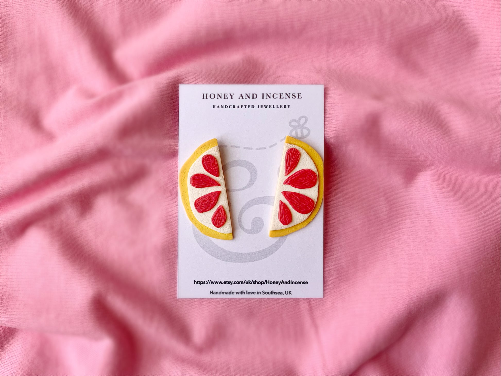 hot pink and yellow statement stud earrings that look like pink grapefruit slices