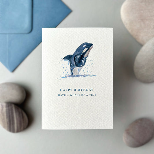 Birthday card with whale illustration and text on a stone surface