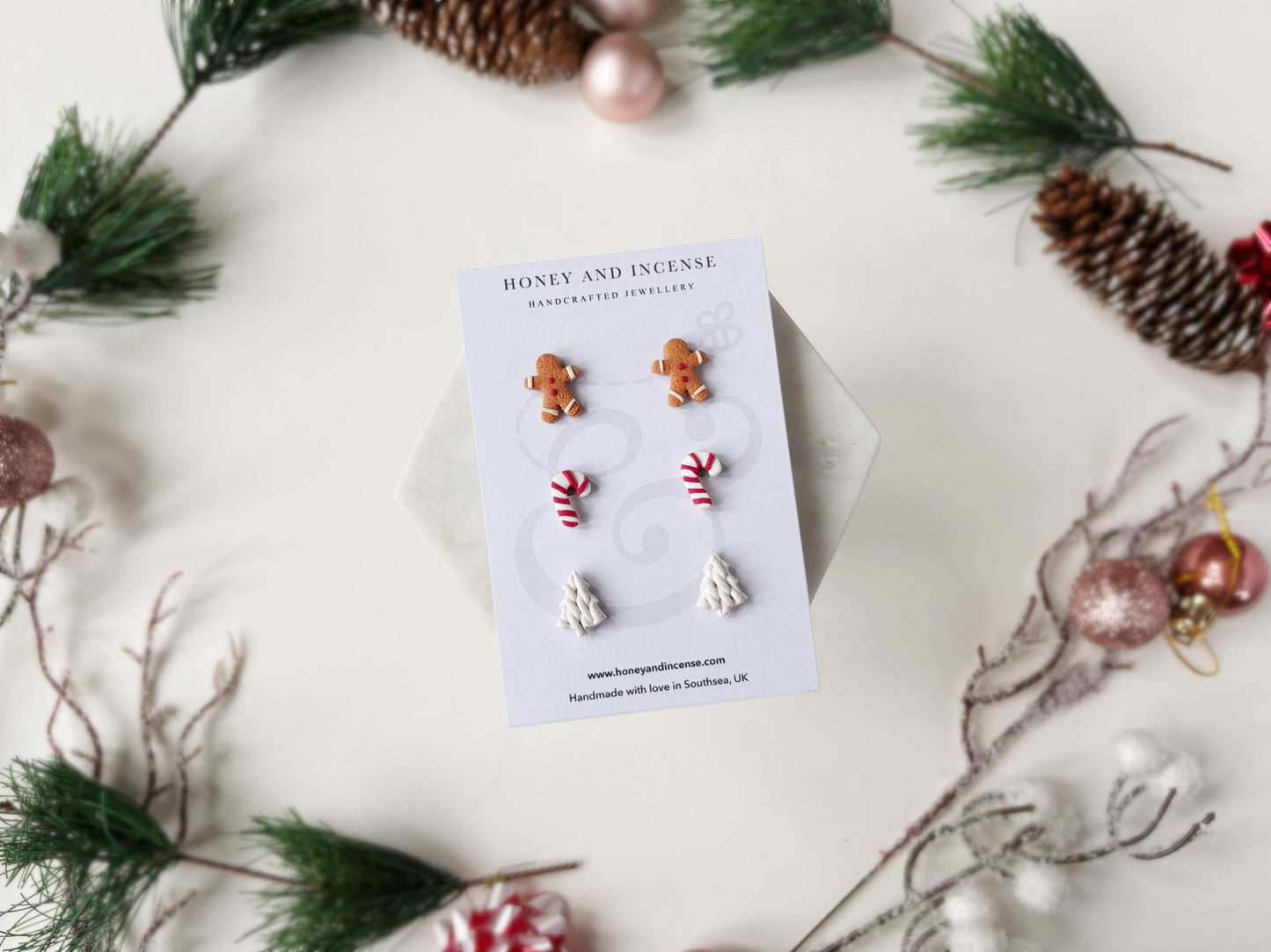 A multipack of 3 pairs of polymer clay stud earrings, gingerbread men, candy canes and white knitted trees 