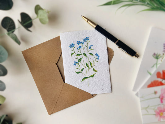 a greetings card containing seeds and a forget me not painting on the front.