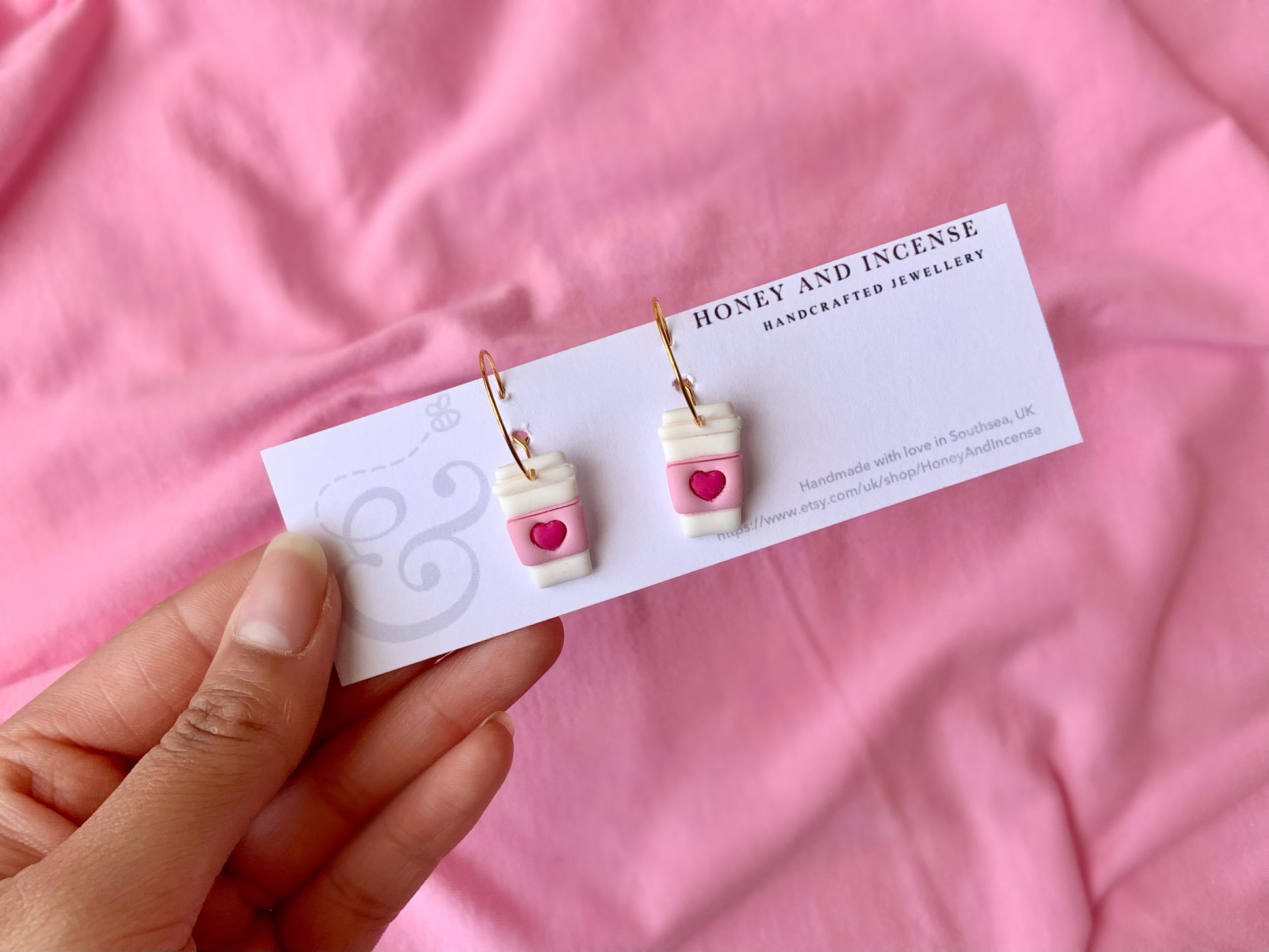 white coffee cup earrings with a pink wrap around and hot pink heart, on gold hoops 