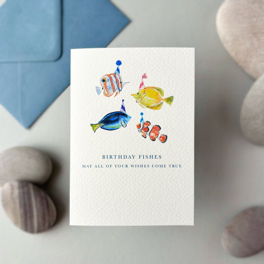 Greeting card with colorful fish illustrations and a blue envelope on a stone surface