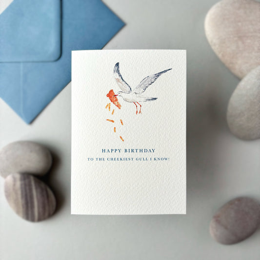 Birthday card, with an illustration of a seagull carrying fish and chips, on a stone surface