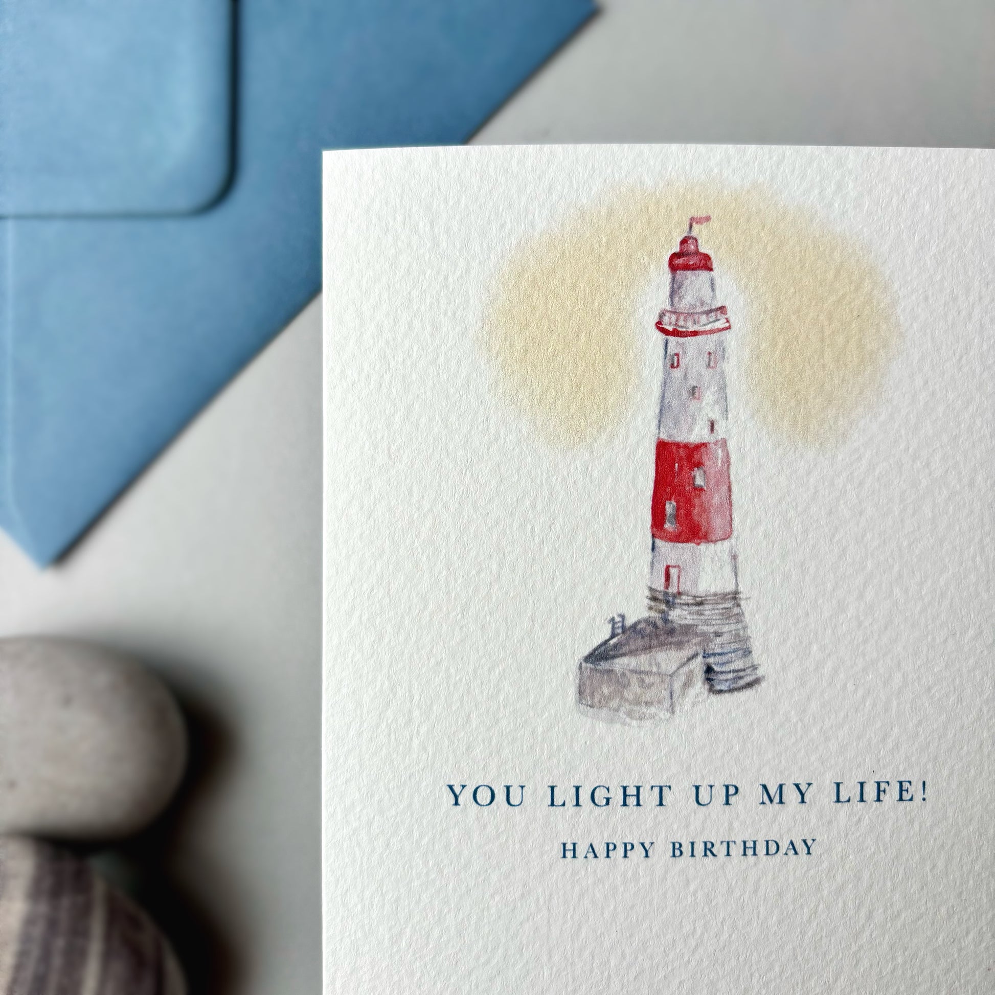 Greeting card with a lighthouse illustration and text 'You light up my life! Happy Birthday' on a white background.