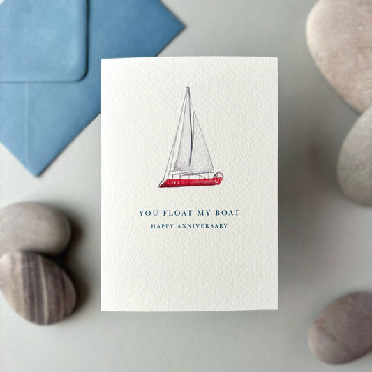 Card with sailboat illustration and 'You Float My Boat' text on a stone surface