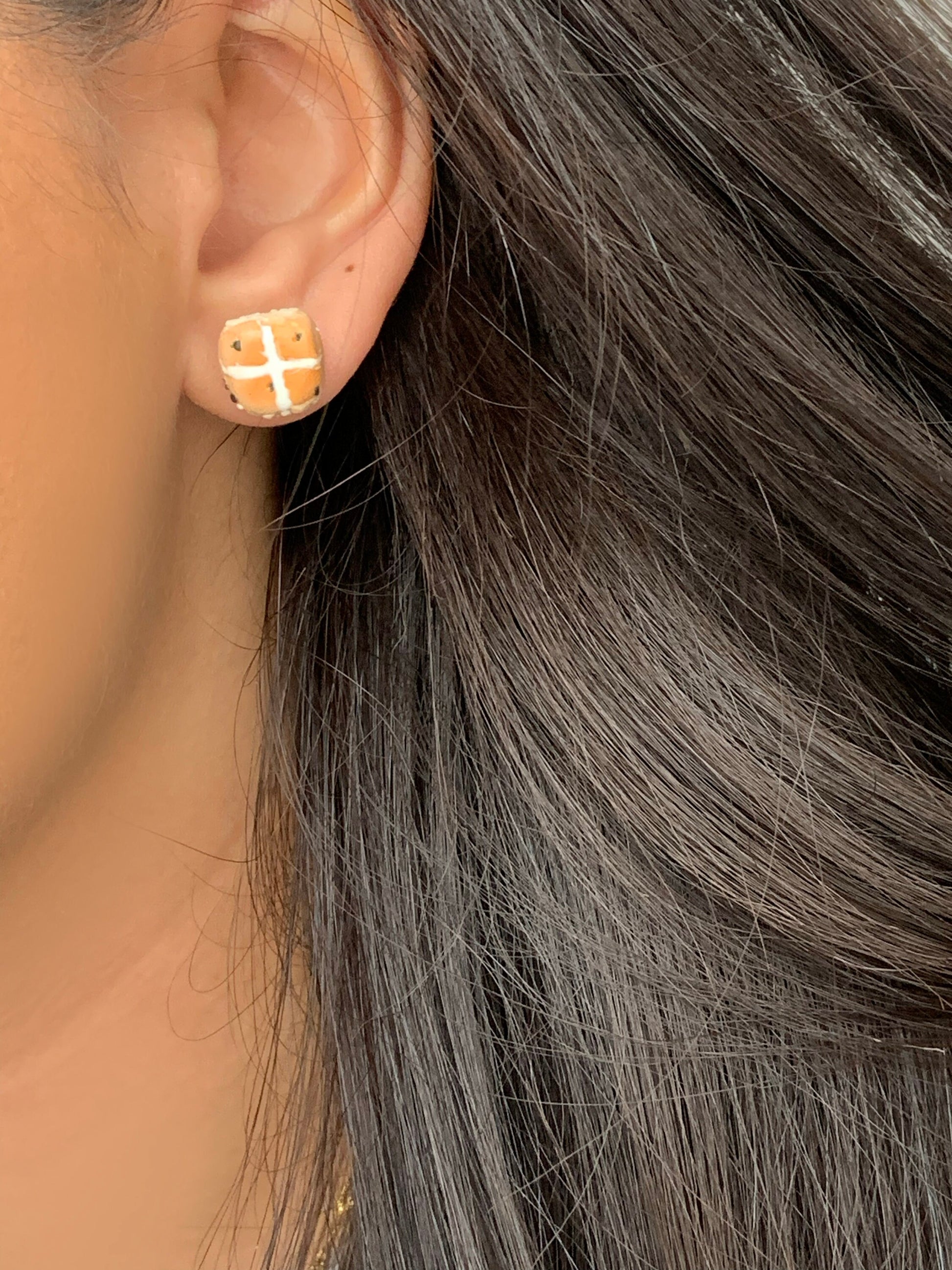 hot cross bun stud earrings for easter, being worn by a model