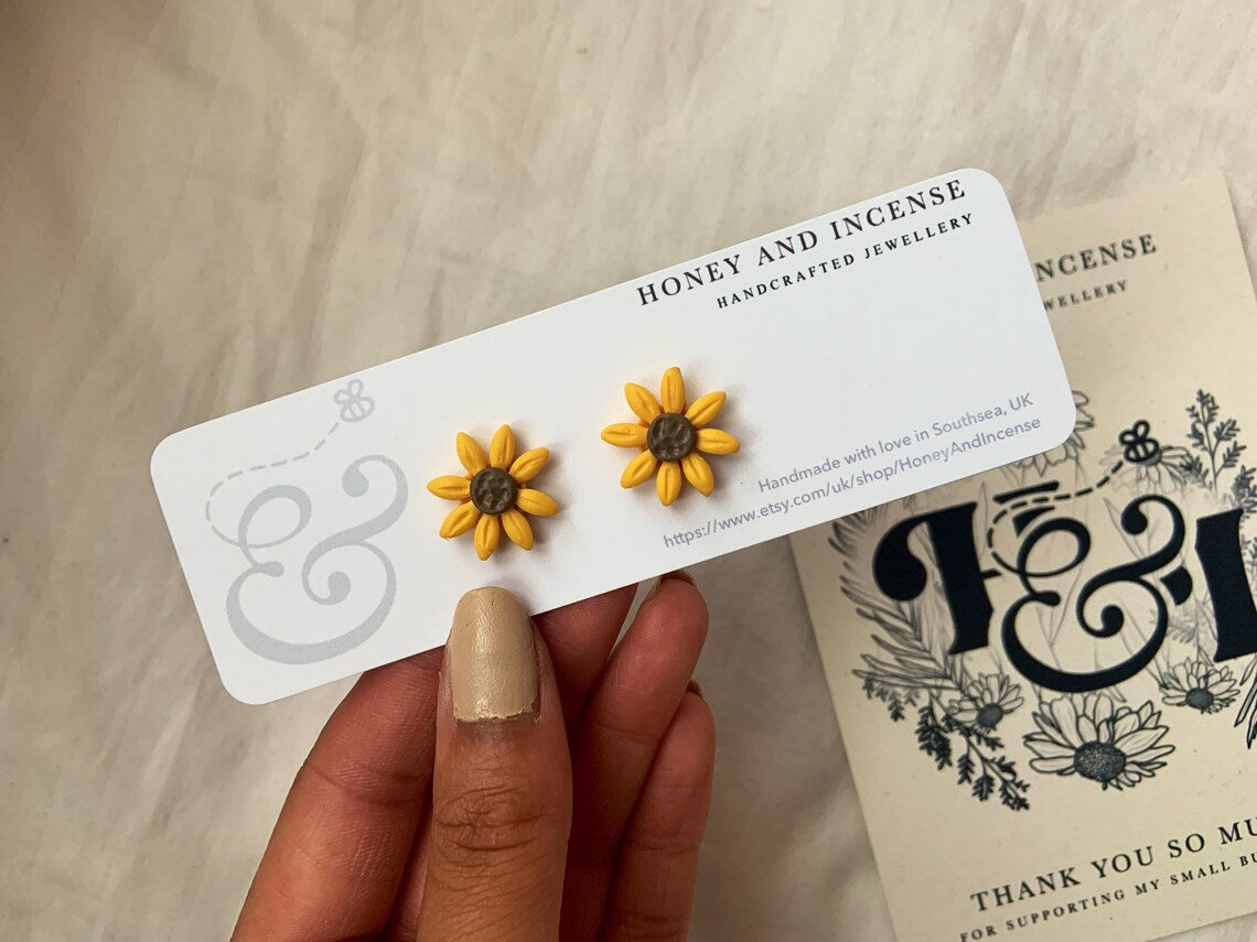 polymer clay sunflower stud earrings shown on a backing card, yellow flower polymer clay studs